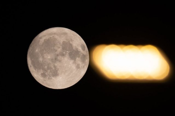 Full super moon is seen next to a street lamp light in L'Aquila, Italy, on July 2, 2023