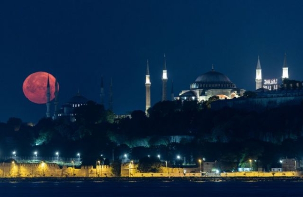 A full moon sets behind the Blue Mosque and the Hagia Sophia Grand Mosque, in Istanbul, Turkey, 03 July 2023