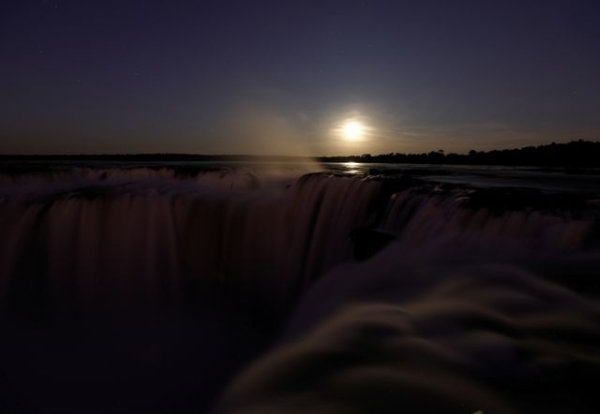 The full moon rising behind the Iguazu Falls, on the Argentine side of the Igauzu River on 3 July