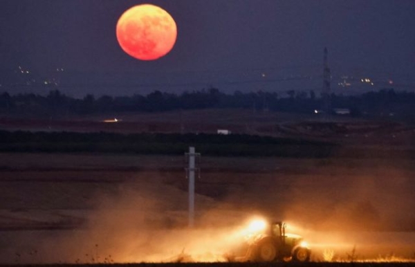 A tractor ploughs a field underneath the supermoon near the city of Ashkelon, in southern Israel, on 3 July